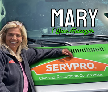 Office Manager leans on green SERVPRO® truck to pose for picture